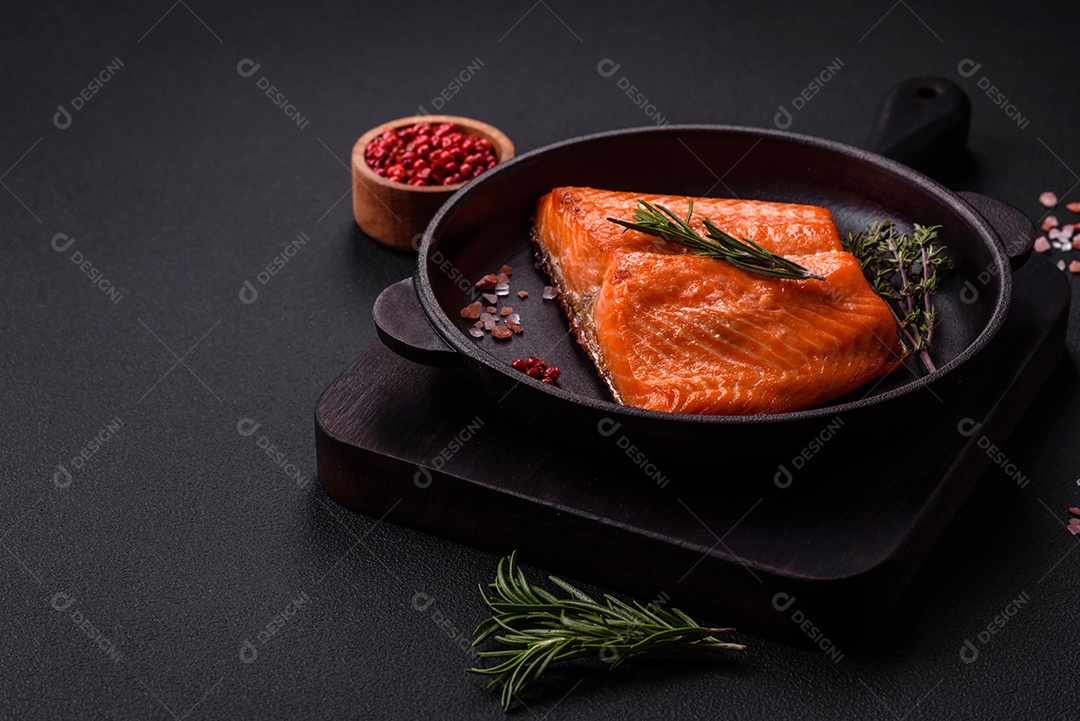 Delicioso filé de peixe vermelho salmão cozido com especiarias e ervas sobre um fundo escuro de concreto