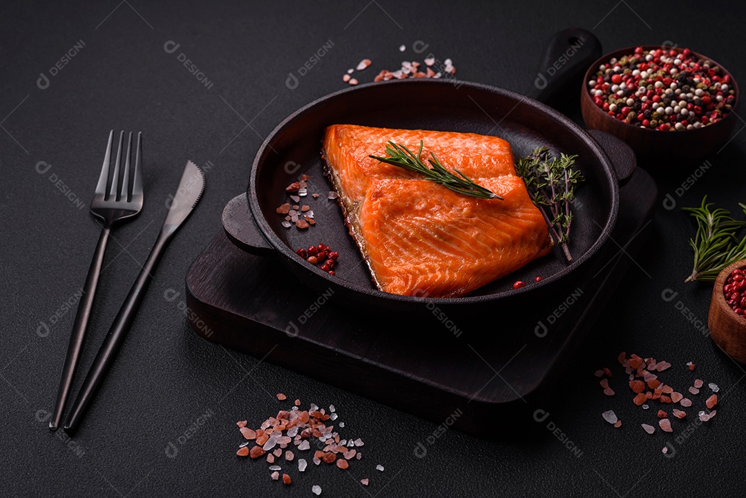 Filé de peixe salmão vermelho cru com sal, especiarias e ervas sobre um fundo escuro de concreto