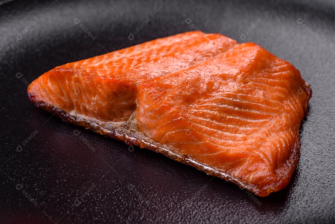 Delicioso filé de peixe vermelho salmão cozido com especiarias e ervas sobre um fundo escuro de concreto