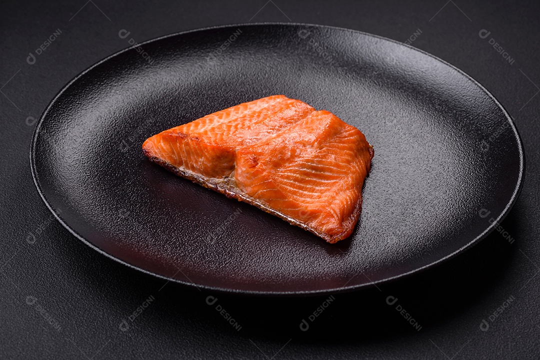 Delicioso filé de peixe vermelho salmão cozido com especiarias e ervas sobre um fundo escuro de concreto