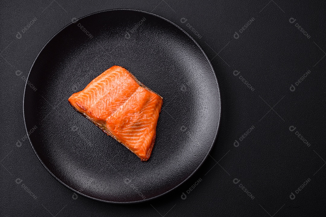 Delicioso filé de peixe vermelho salmão cozido com especiarias e ervas sobre um fundo escuro de concreto