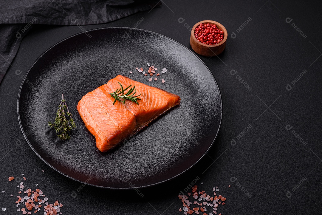 Delicioso filé de peixe vermelho salmão cozido com especiarias e ervas sobre um fundo escuro de concreto