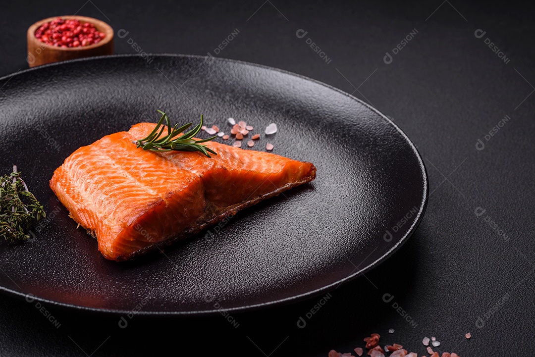 Delicioso filé de peixe vermelho salmão cozido com especiarias e ervas sobre um fundo escuro de concreto