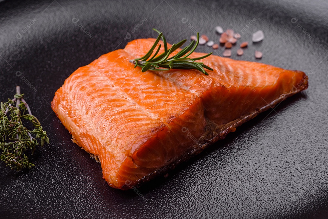Delicioso filé de peixe vermelho salmão cozido com especiarias e ervas sobre um fundo escuro de concreto