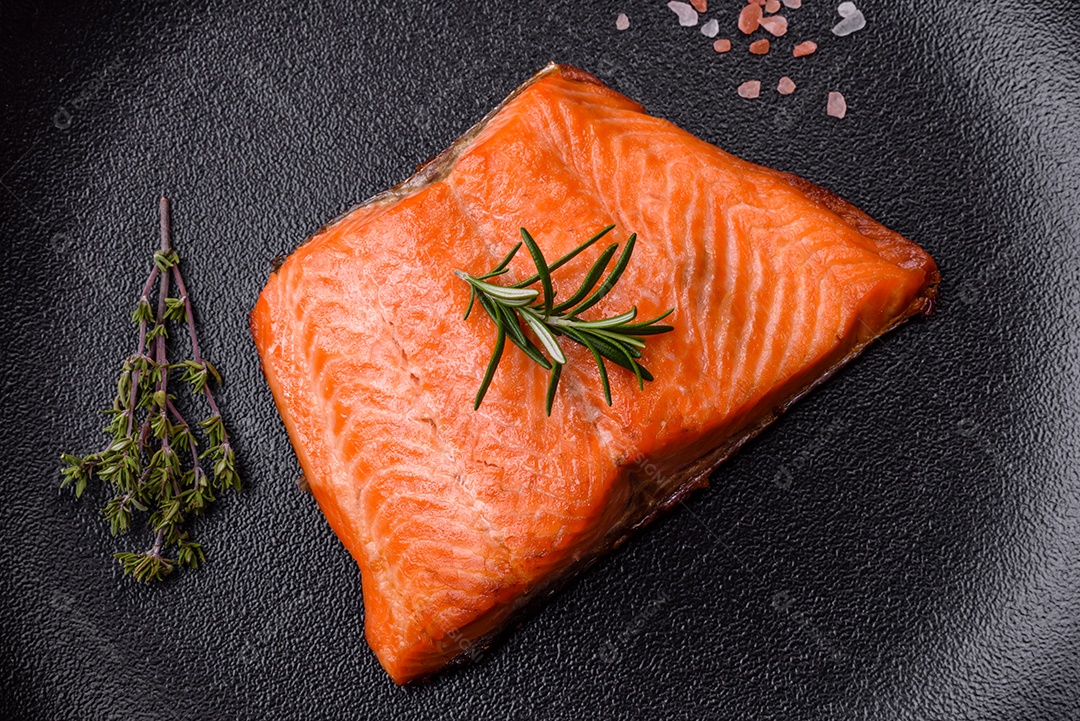 Delicioso filé de peixe vermelho salmão cozido com especiarias e ervas sobre um fundo escuro de concreto