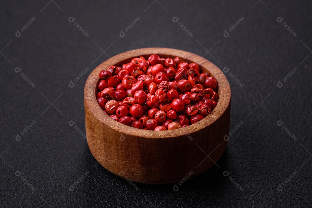 Ervilhas de pimenta da Jamaica em uma tigela de madeira sobre um fundo preto de concreto. Preparando temperos para cozinhar em casa