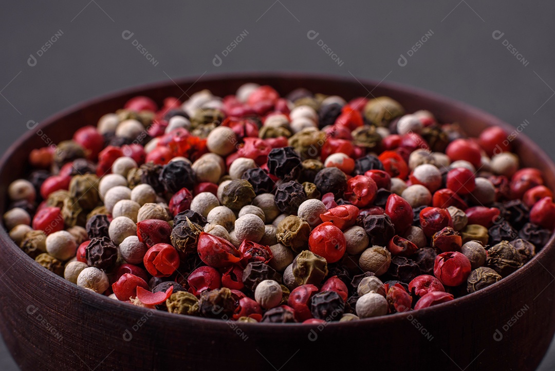 Ervilhas de pimenta da Jamaica em uma tigela de madeira sobre um fundo preto de concreto. Preparando temperos para cozinhar em casa