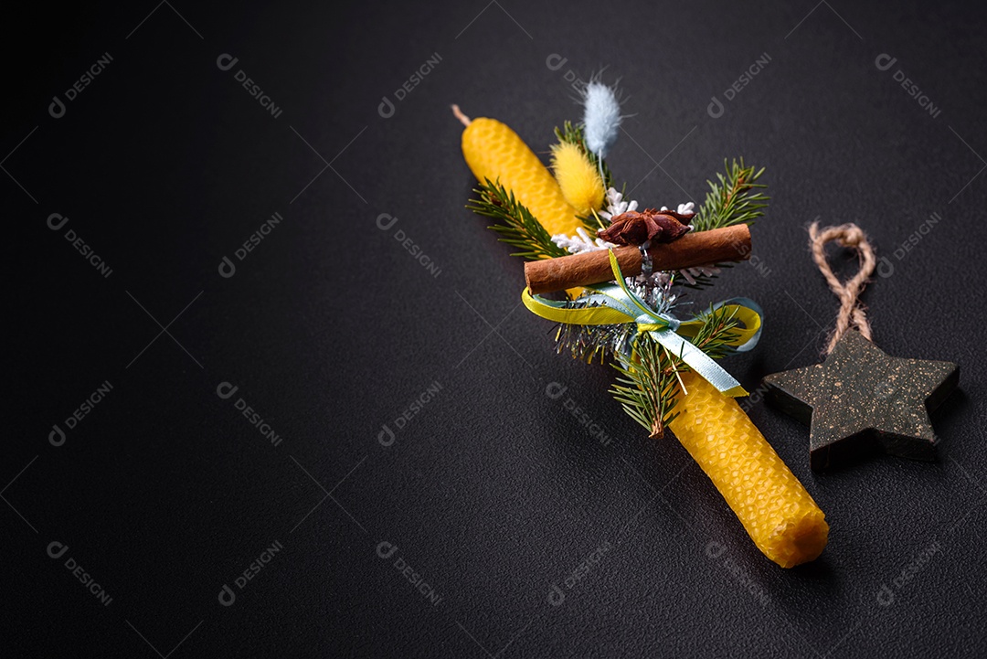 Vela decorada com decorações de Natal em um fundo escuro de concreto. Decoração de casa de férias