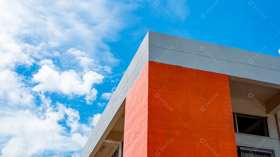 Edifício laranja sobre um fundo de céu e nuvens brancas.