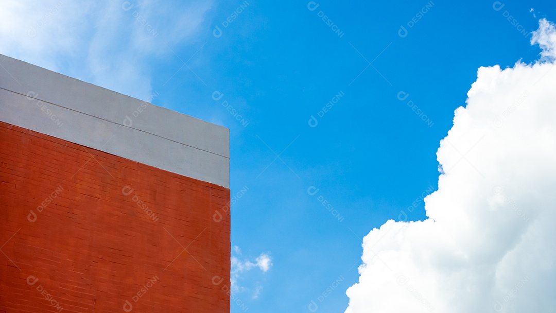 Edifício laranja sobre um fundo de céu e nuvens brancas.