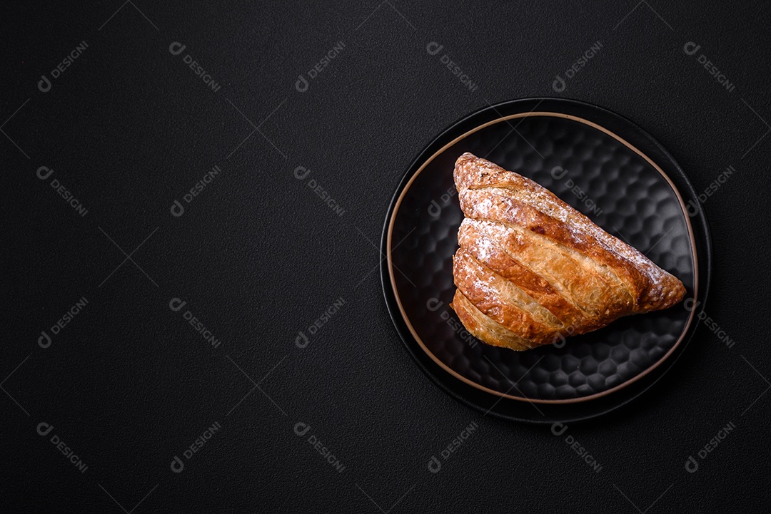 Delicioso pão crocante fresco com geléia em uma placa de cerâmica preta sobre um fundo escuro de concreto