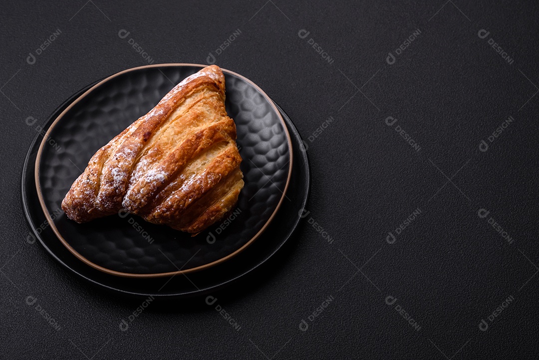Delicioso pão crocante fresco com geléia em uma placa de cerâmica preta sobre um fundo escuro de concreto