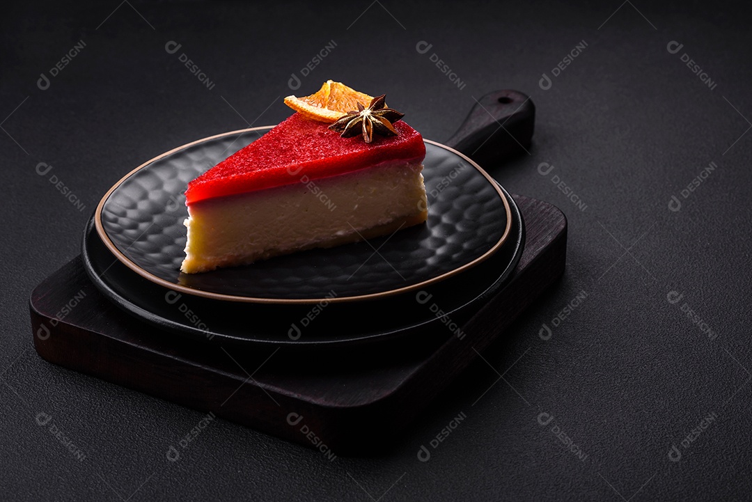 Delicioso cheesecake doce com geléia de framboesa em uma placa de cerâmica preta sobre um fundo escuro de concreto