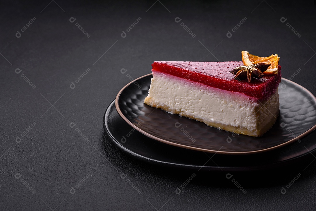 Delicioso cheesecake doce com geléia de framboesa em uma placa de cerâmica preta sobre um fundo escuro de concreto