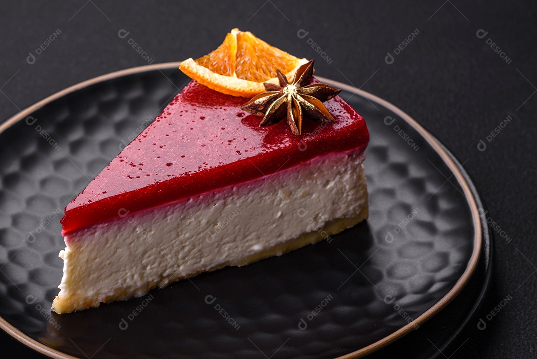 Delicioso cheesecake doce com geléia de framboesa em uma placa de cerâmica preta sobre um fundo escuro de concreto