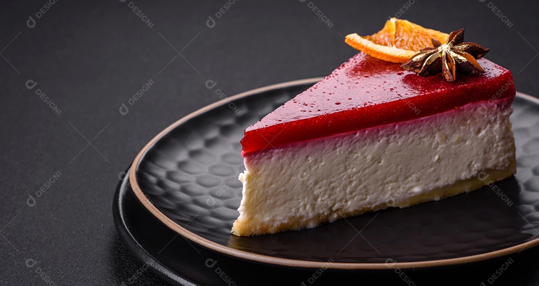 Delicioso cheesecake doce com geléia de framboesa em uma placa de cerâmica preta sobre um fundo escuro de concreto