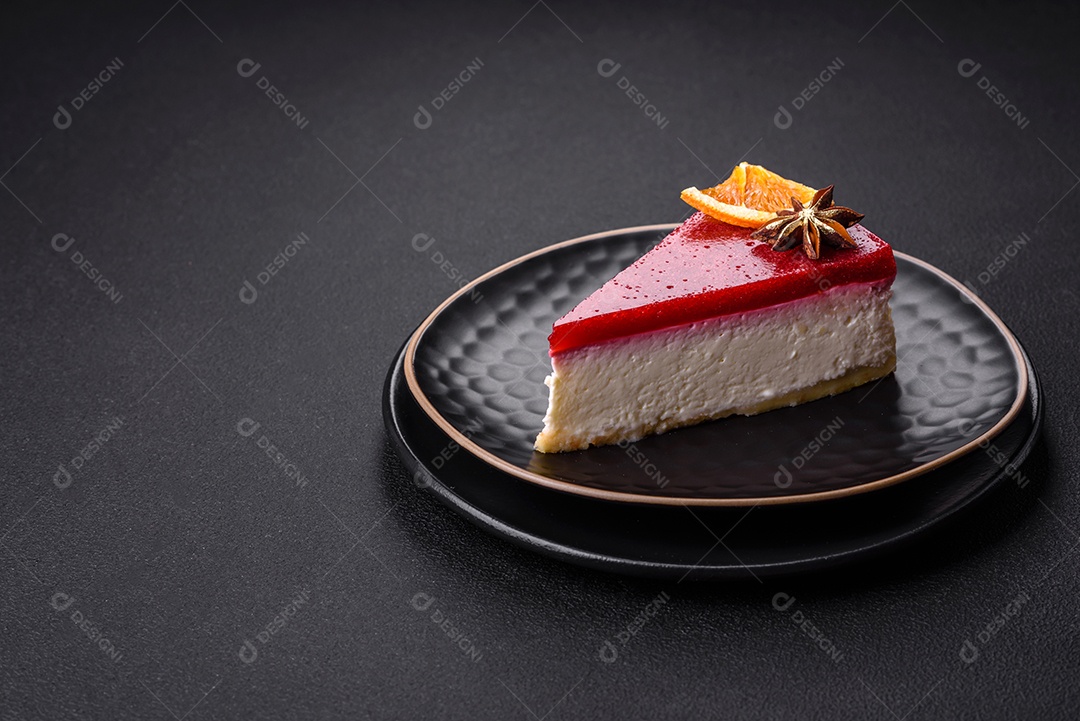 Delicioso cheesecake doce com geléia de framboesa em uma placa de cerâmica preta sobre um fundo escuro de concreto