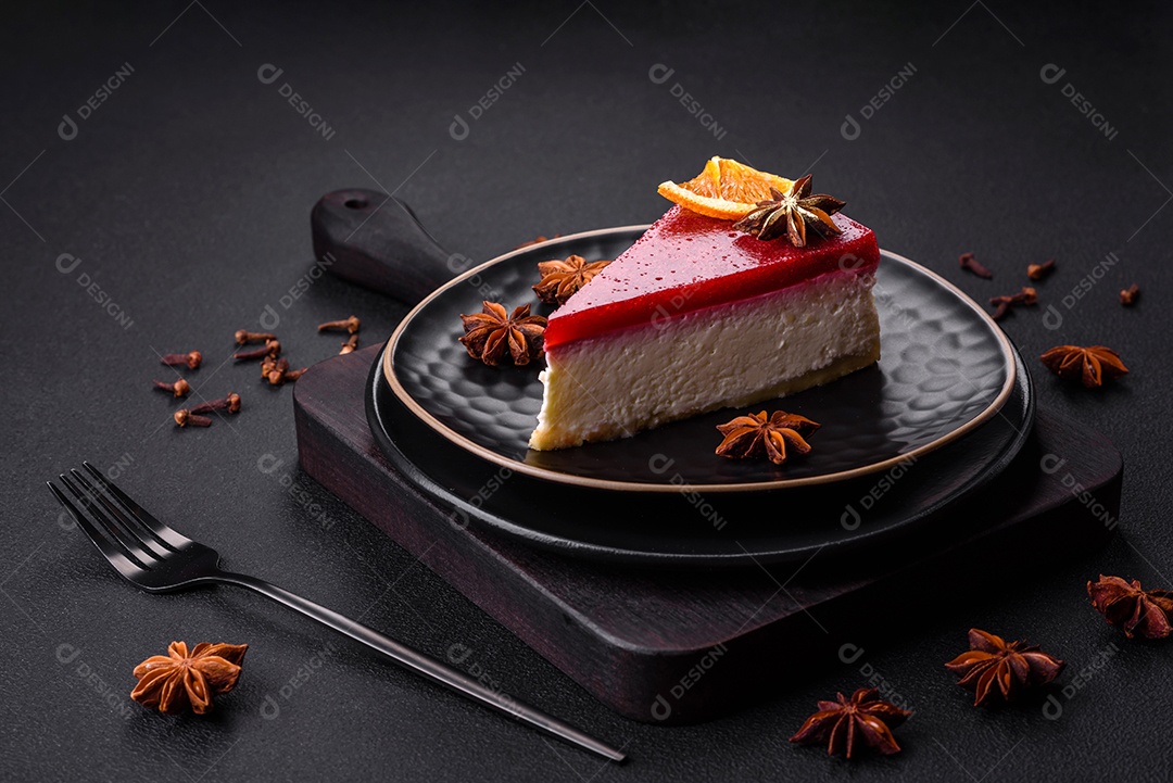Delicioso cheesecake doce com geléia de framboesa em uma placa de cerâmica preta sobre um fundo escuro de concreto