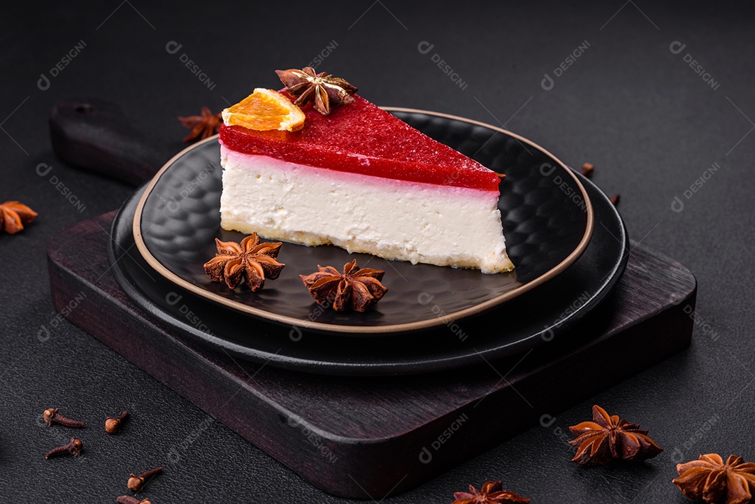 Delicioso cheesecake doce com geléia de framboesa em uma placa de cerâmica preta sobre um fundo escuro de concreto