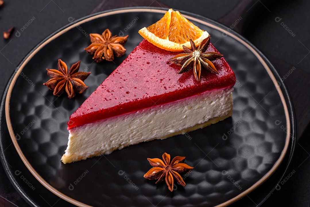 Delicioso cheesecake doce com geléia de framboesa em uma placa de cerâmica preta sobre um fundo escuro de concreto
