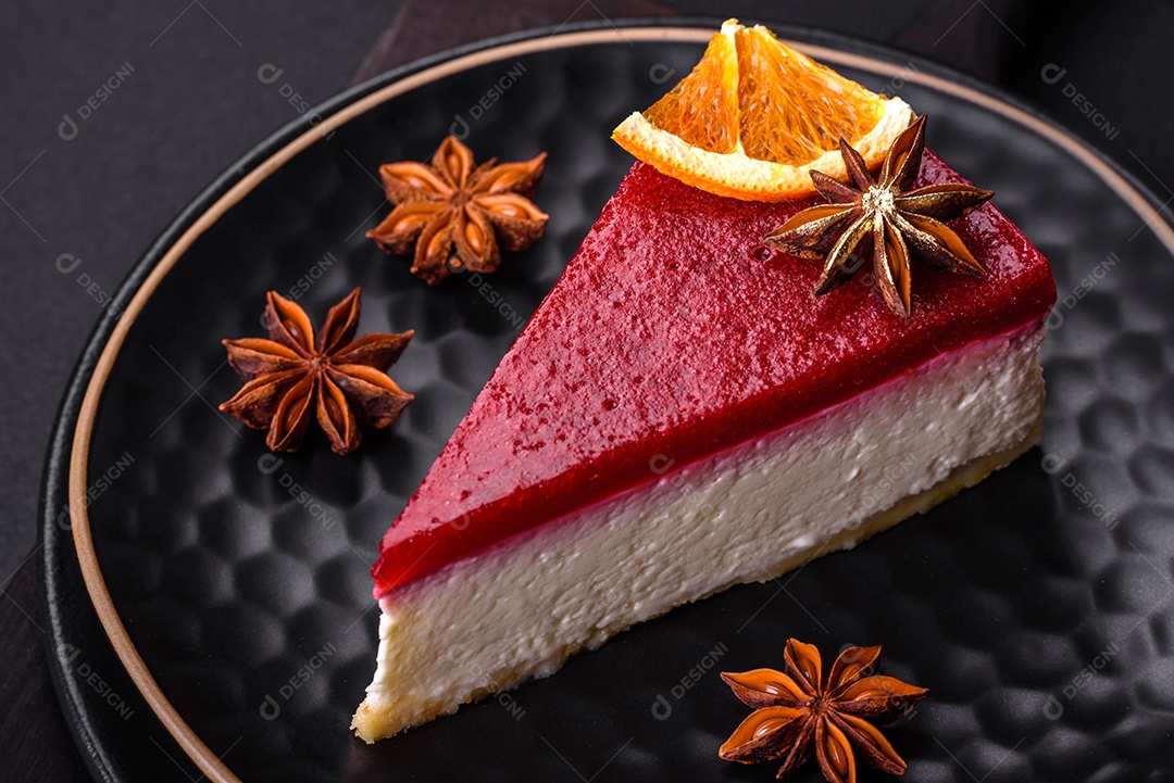 Delicioso cheesecake doce com geléia de framboesa em uma placa de cerâmica preta sobre um fundo escuro de concreto