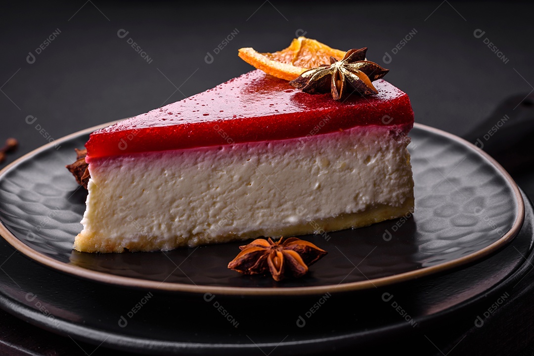 Delicioso cheesecake doce com geléia de framboesa em uma placa de cerâmica preta sobre um fundo escuro de concreto