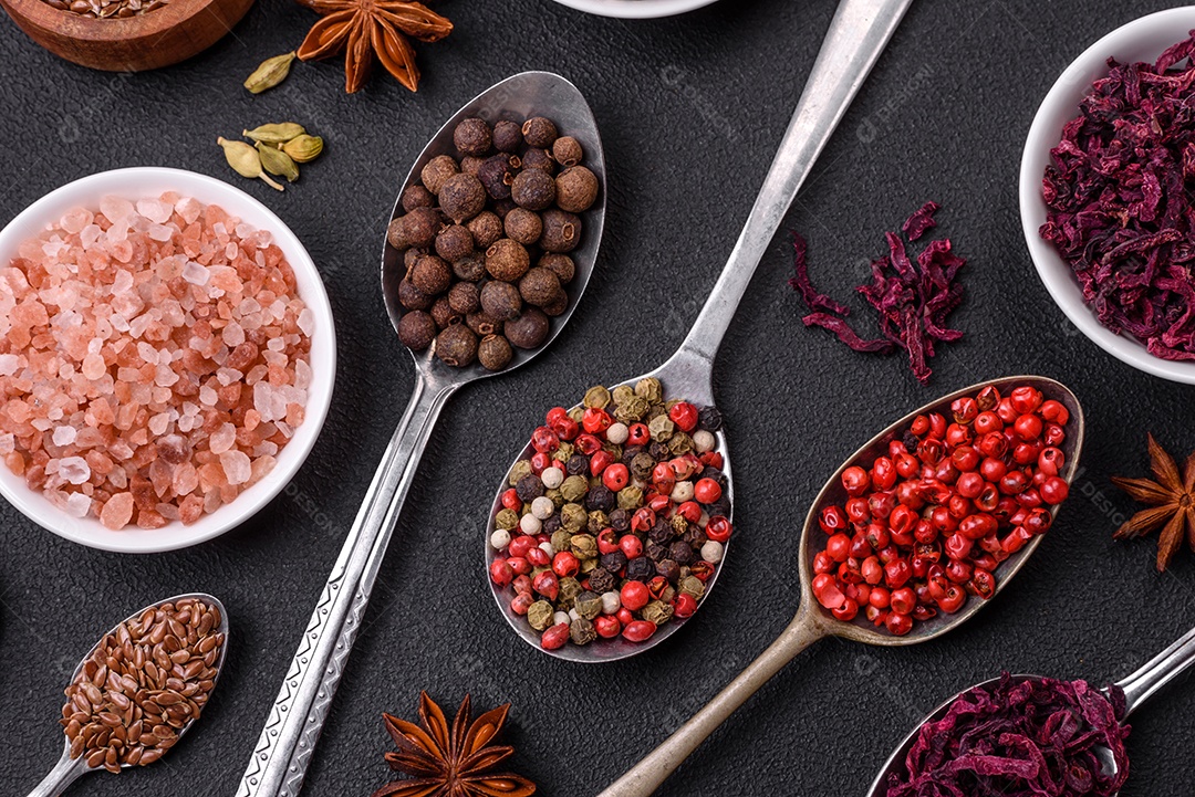 Composição composta por uma variação de diversos tipos de especiarias em tigelas de cerâmica branca sobre fundo de concreto texturizado