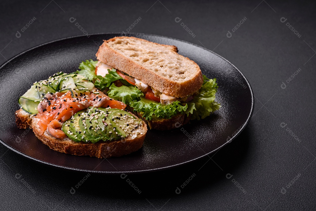 Sanduíche fresco e saboroso com salmão, abacate e sementes de gergelim e linho sobre um fundo escuro de concreto