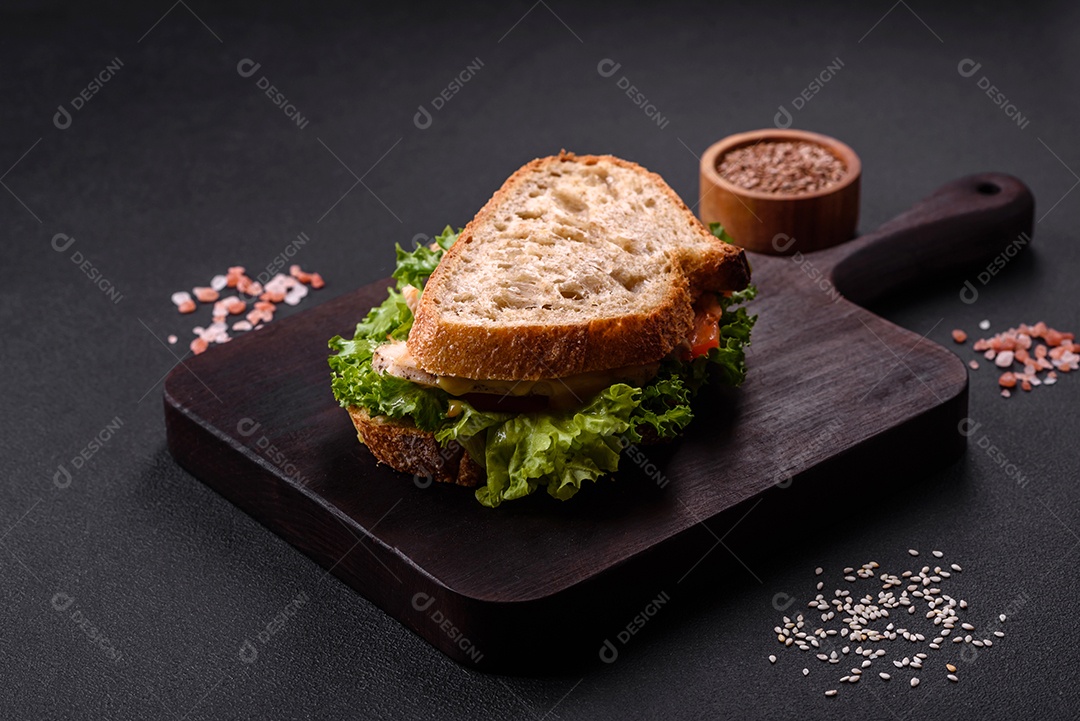 Sanduíche fresco e saboroso com salmão, abacate e sementes de gergelim e linho sobre um fundo escuro de concreto