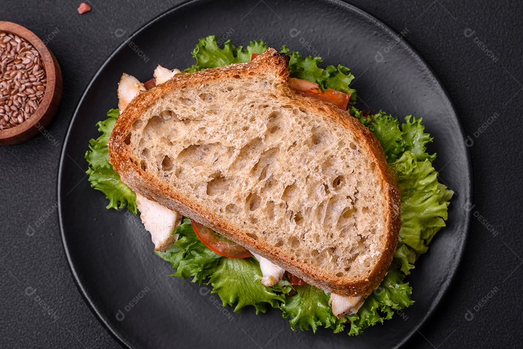 Sanduíche fresco e saboroso com salmão, abacate e sementes de gergelim e linho sobre um fundo escuro de concreto