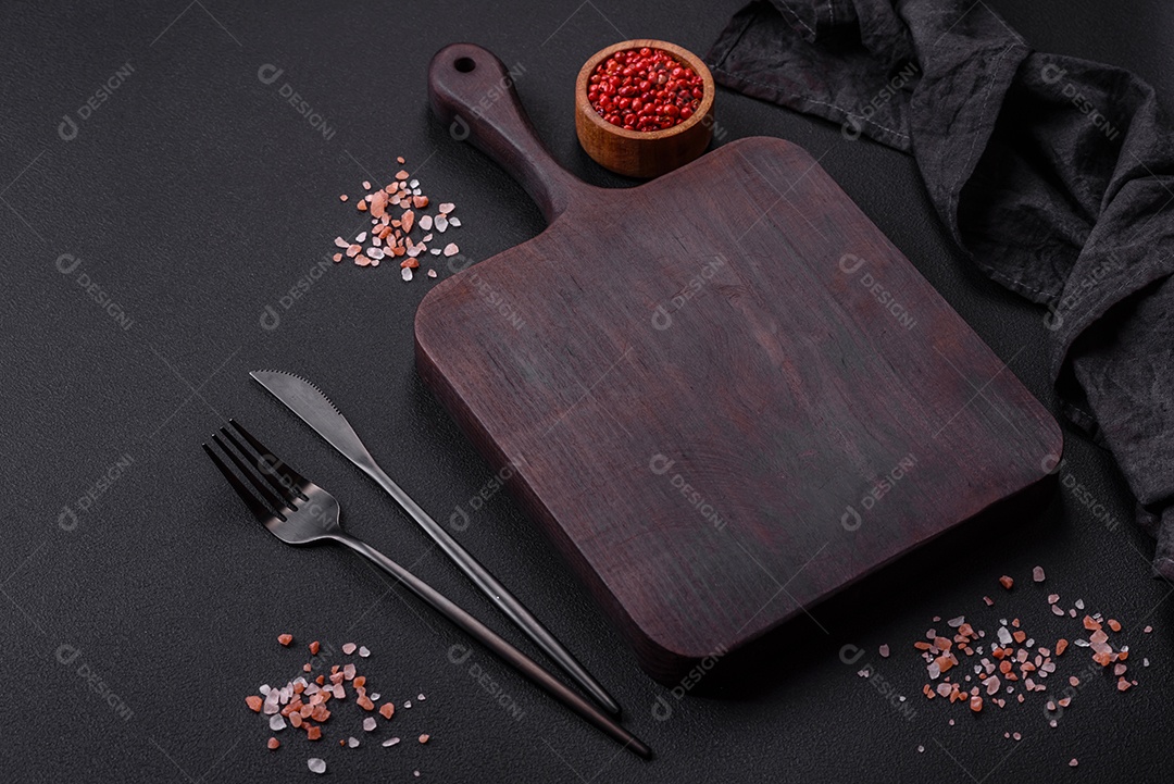 Tábua de madeira vazia com especiarias e ervas em fundo escuro de concreto