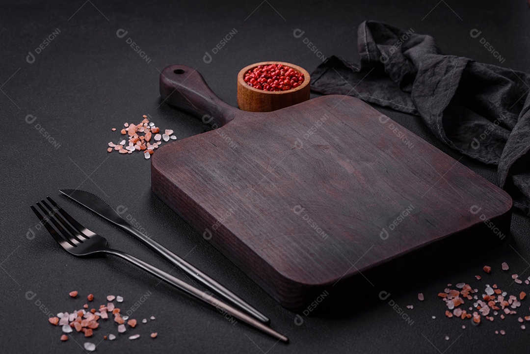 Tábua de madeira vazia com especiarias e ervas em fundo escuro de concreto