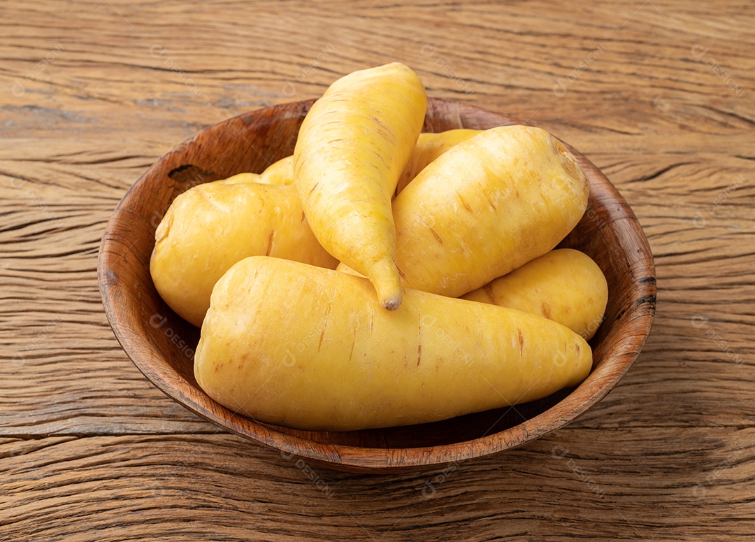 Mandioquinha crua ou mandioquinha em uma tigela sobre mesa de madeira.