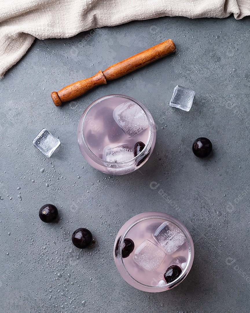 Caipirinha de jabuticaba brasileira em copos com gelo e frutas sobre fundo de pedra.