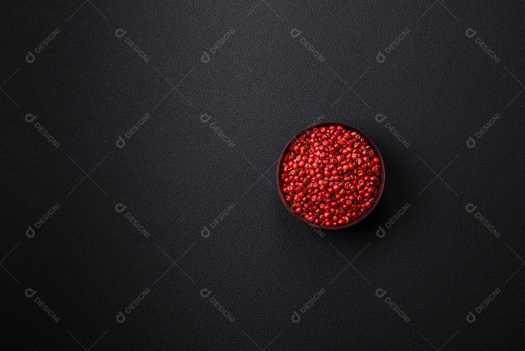 Especiarias, ervilhas de pimenta da Jamaica na cor vermelha ou rosa em uma tigela de madeira sobre um fundo preto de concreto. Cozinha asiática