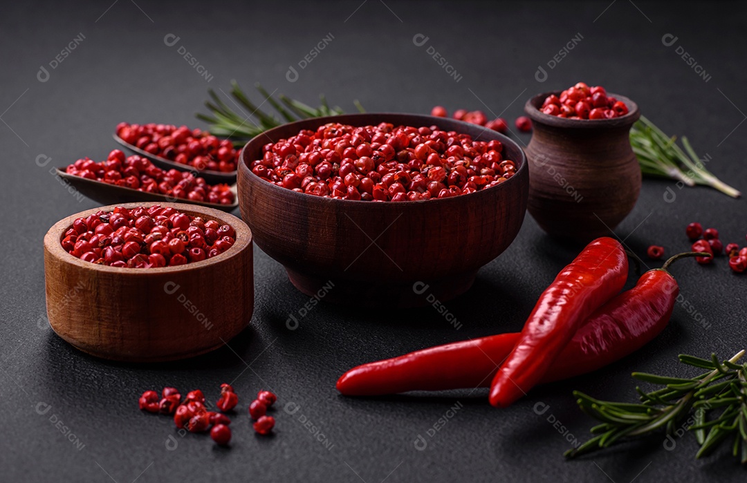 Especiarias, ervilhas de pimenta da Jamaica na cor vermelha ou rosa em uma tigela de madeira sobre um fundo preto de concreto. Cozinha asiática