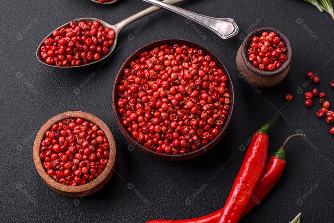 Especiarias, ervilhas de pimenta da Jamaica na cor vermelha ou rosa em uma tigela de madeira sobre um fundo preto de concreto. Cozinha asiática