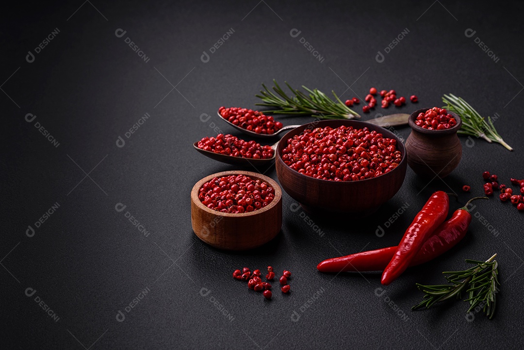 Especiarias, ervilhas de pimenta da Jamaica na cor vermelha ou rosa em uma tigela de madeira sobre um fundo preto de concreto. Cozinha asiática