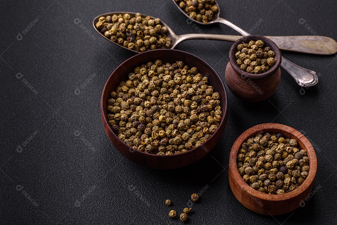 Especiarias, pimenta da Jamaica verde em uma tigela de madeira sobre um fundo preto de concreto. Cozinha asiática