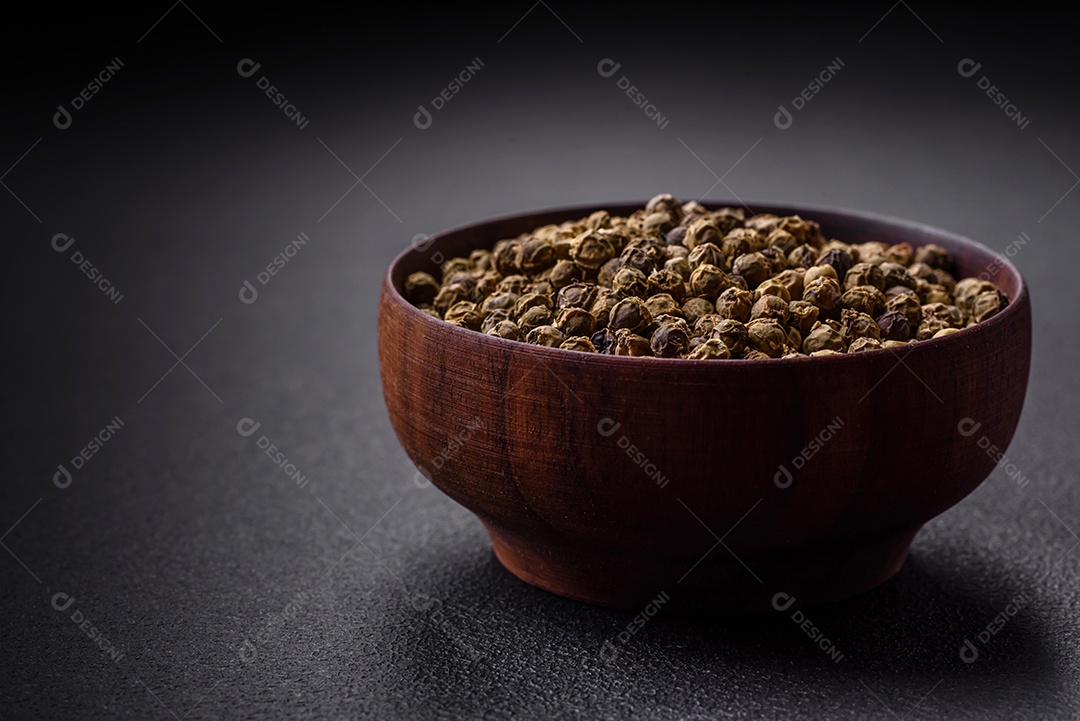Especiarias, pimenta da Jamaica verde em uma tigela de madeira sobre um fundo preto de concreto. Cozinha asiática