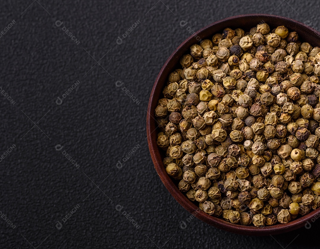 Especiarias, pimenta da Jamaica verde em uma tigela de madeira sobre um fundo preto de concreto. Cozinha asiática