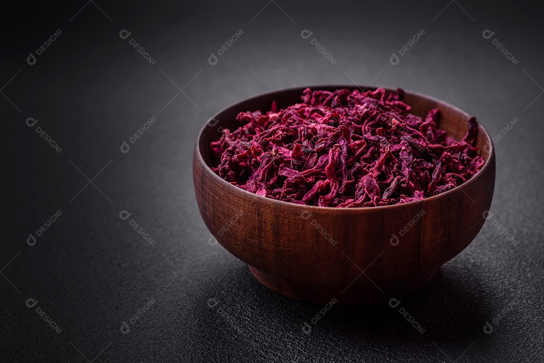 Beterrabas secas em pequenas fatias em uma tigela de madeira sobre um fundo preto de concreto. Cozinha asiática