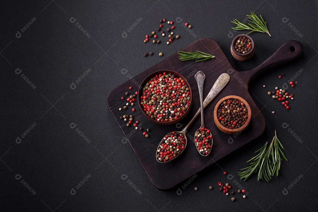 Pimenta da Jamaica de cores diferentes, rosa, branco, verde, não moída em um pires de madeira sobre um fundo escuro de concreto