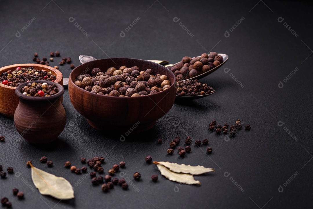 Especiaria de cor marrom pimenta da Jamaica não moída em um pires de madeira sobre um fundo escuro de concreto