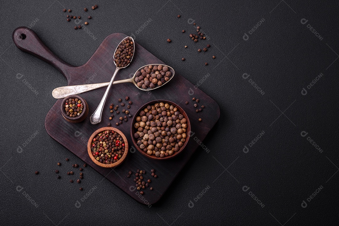 Especiaria de cor marrom pimenta da Jamaica não moída em um pires de madeira sobre um fundo escuro de concreto