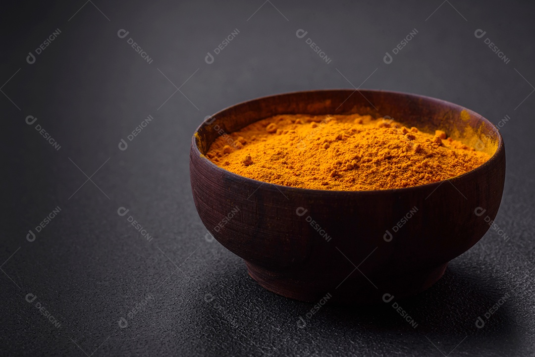 Cúrcuma amarela brilhante ou tempero de curry para preparação de alimentos asiáticos em fundo escuro de concreto