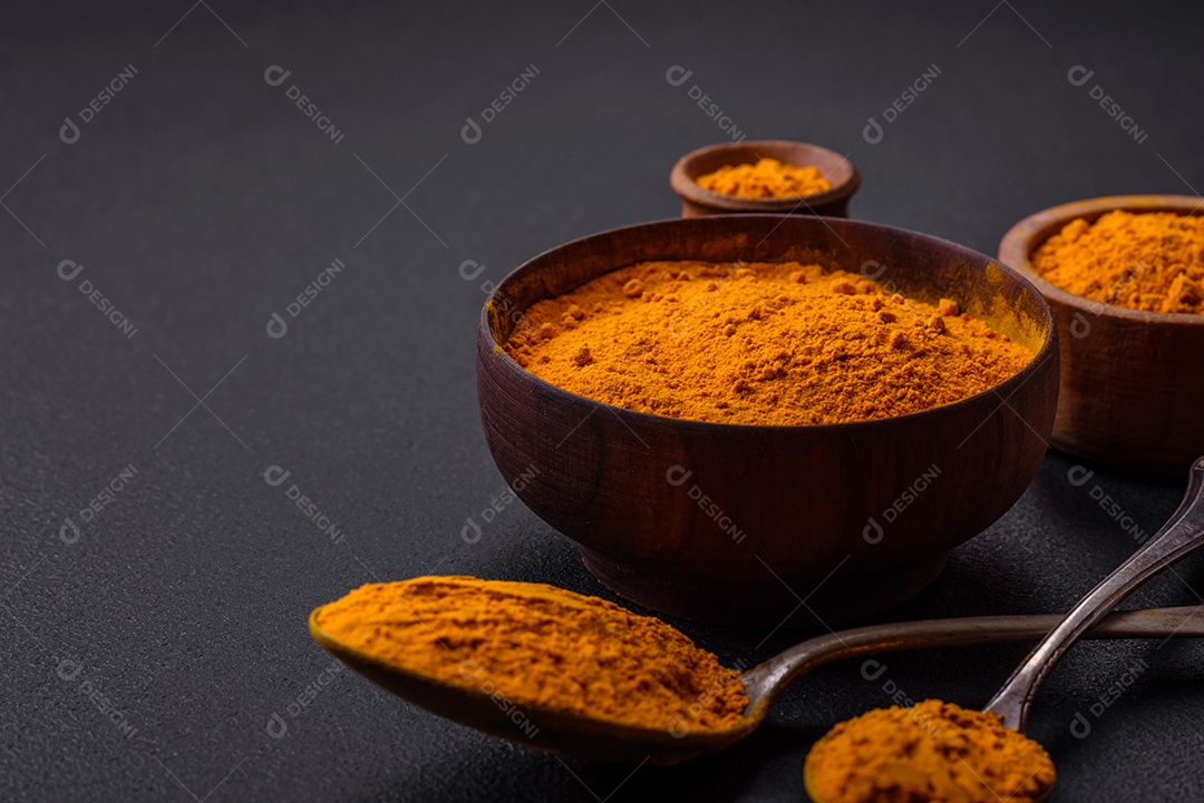 Cúrcuma amarela brilhante ou tempero de curry para preparação de alimentos asiáticos em fundo escuro de concreto