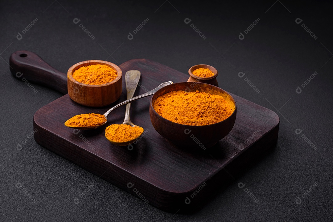 Cúrcuma amarela brilhante ou tempero de curry para preparação de alimentos asiáticos em fundo escuro de concreto