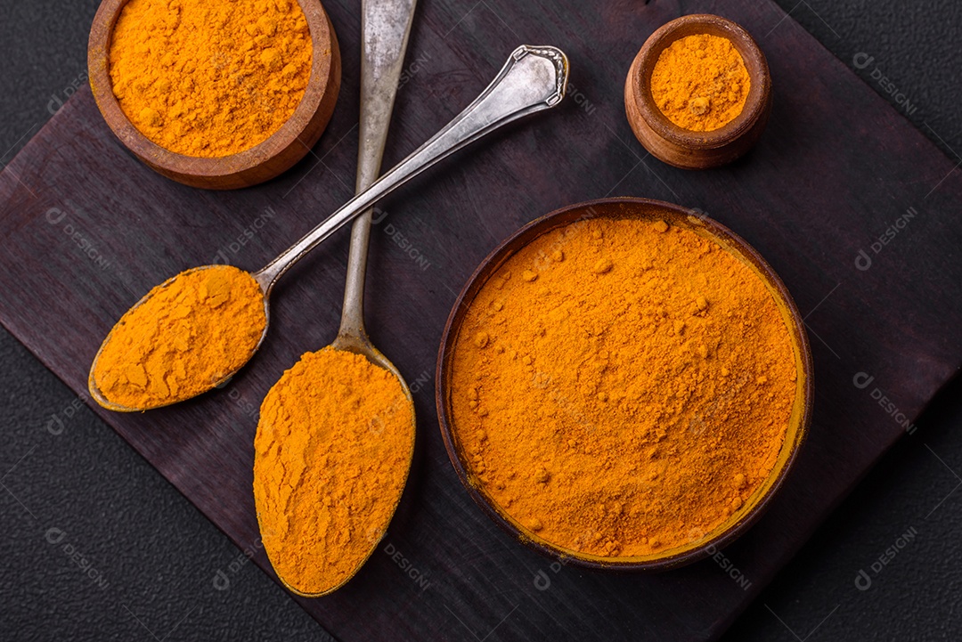 Cúrcuma amarela brilhante ou tempero de curry para preparação de alimentos asiáticos em fundo escuro de concreto