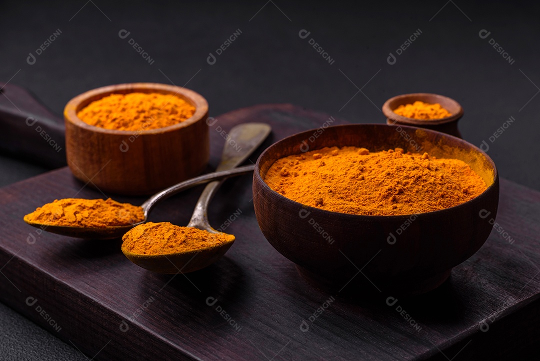 Cúrcuma amarela brilhante ou tempero de curry para preparação de alimentos asiáticos em fundo escuro de concreto